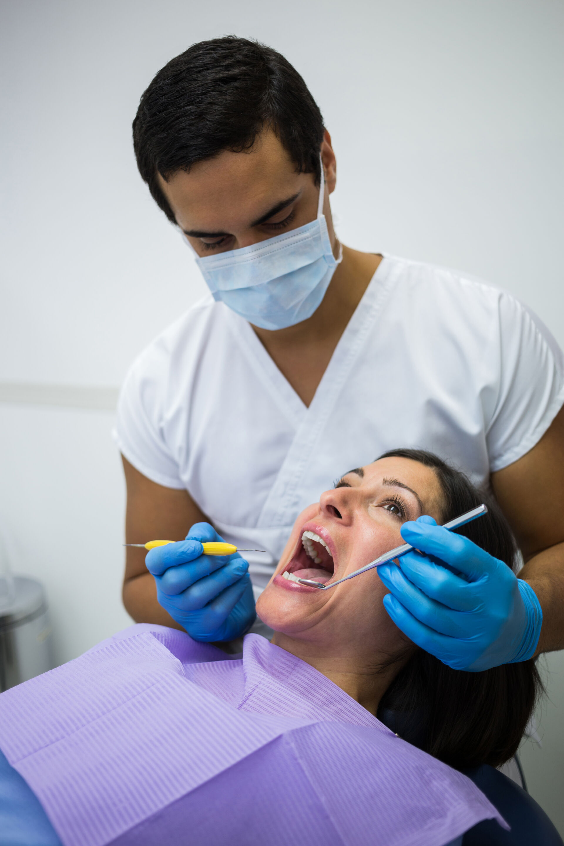 Patient First - Dentist examining female patient teeth at the clinic