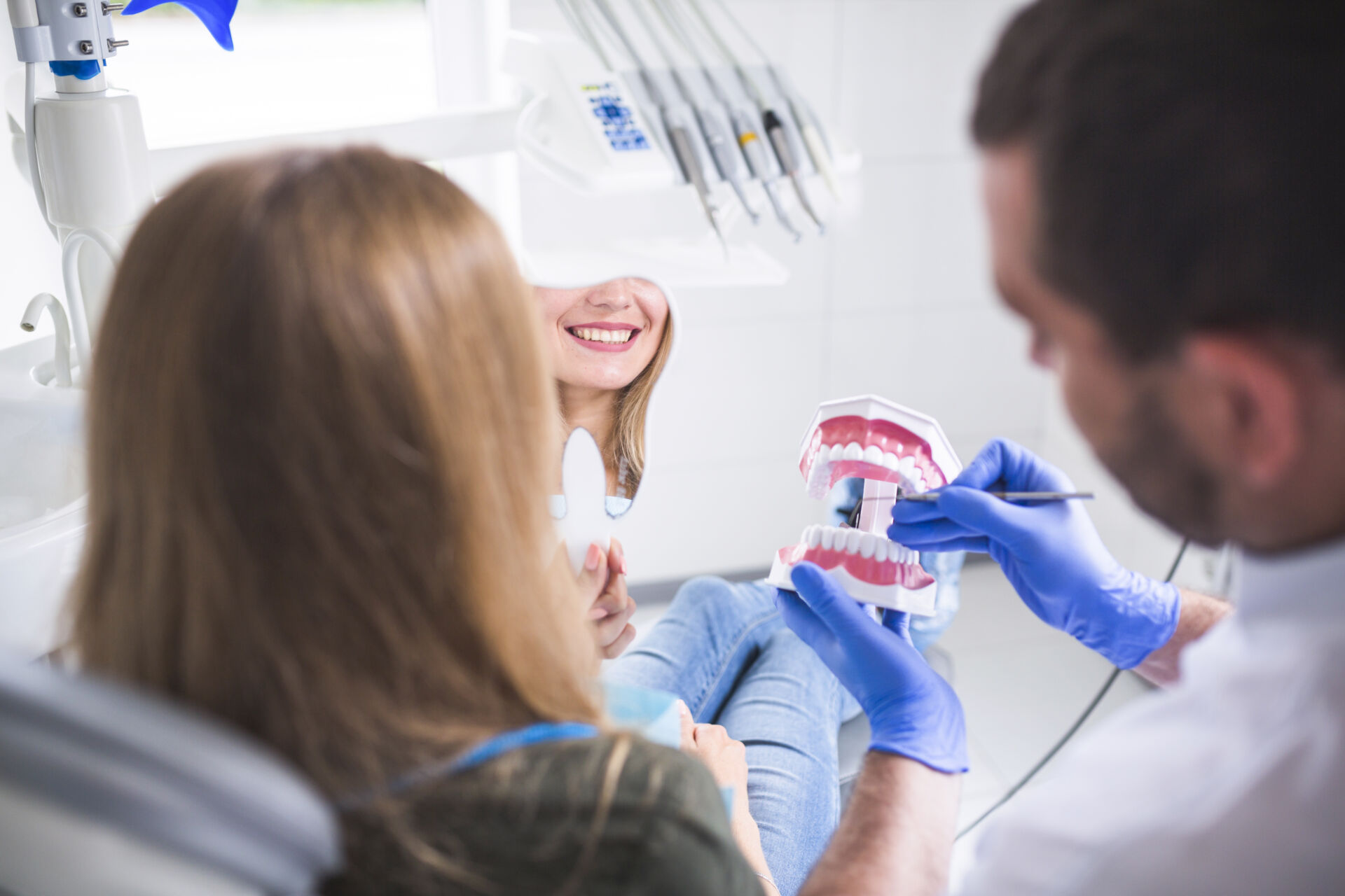 Patient First Dentist showing patient how to clean their teeth using a model of a mouth