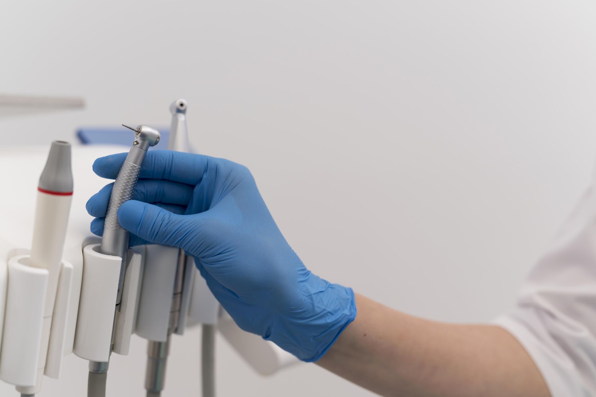 Patient First Dentist picking up equipment to perform hygiene check on patient's teeth